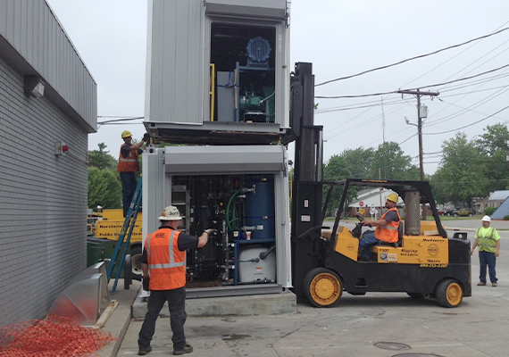 Multiple employees maneuver one remediation system to be stacked on another one.