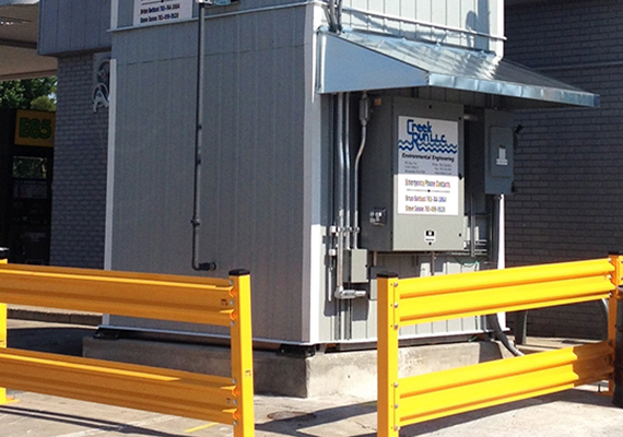 External view of a remediation system build, with grey walls, pipes, and access boxes on the sides.