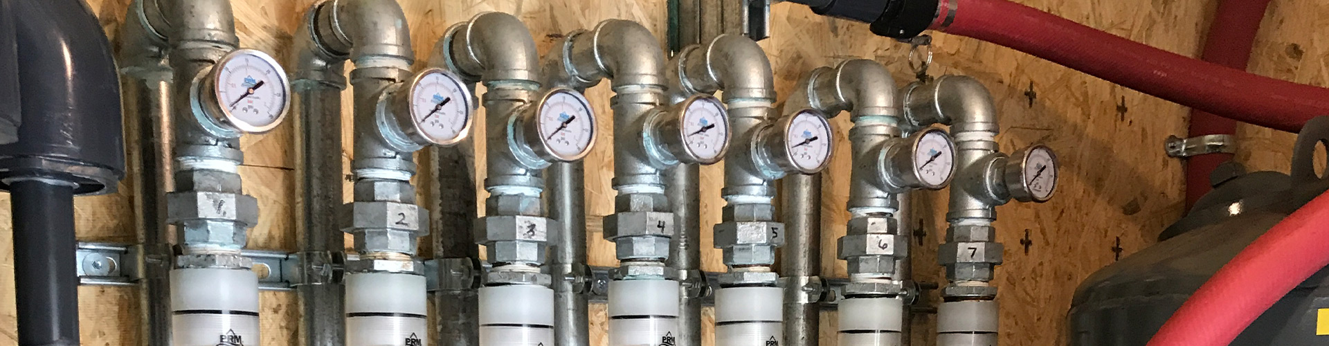 External view of a remediation system build, specifically a row of silver pipes fitted with pressure gauges.